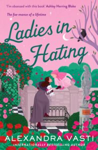 Book cover of Ladies in Hating by Alexandra Vasti featuring two women facing off in a rose garden, one holding a fluffy white dog and the other leaning over a stone wall, set against a pink sky with whimsical details.