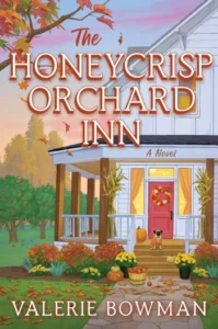 Book cover of The Honeycrisp Orchard Inn by Valerie Bowman featuring a cozy white farmhouse with pumpkins, autumn leaves, and a dog on the front porch.
